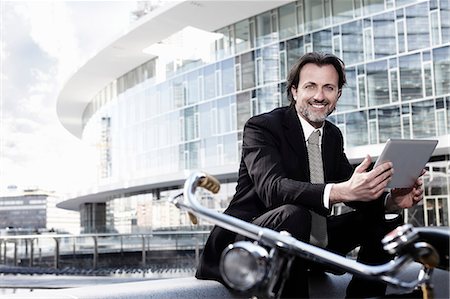 Mid adult businessman using digital tablet in city, portrait Stock Photo - Premium Royalty-Free, Code: 614-08875100