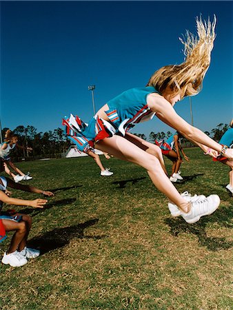 Young cheerleaders performing routine on football field Stock Photo - Premium Royalty-Free, Code: 614-08875250