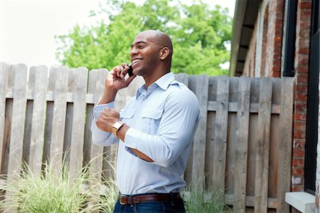 person standing and talking on phone - Mid adult man using mobile phone in garden, smiling Stock Photo - Premium Royalty-Free, Code: 614-08875366
