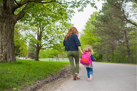 simsearch:614-08875430,k - Rear view of mother and daughter holding hands walking down road through woods Fotografie stock - Premium Royalty-Free, Codice: 614-08875420