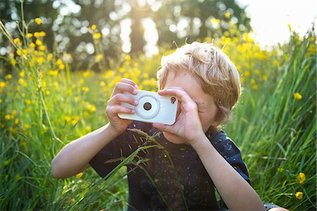 simsearch:614-06442908,k - Boy sitting in long grass taking photograph using smartphone Stock Photo - Premium Royalty-Free, Code: 614-08875444