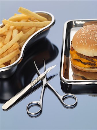 Burger and fries sitting in surgical trays illustrating unhealthy diet Stock Photo - Premium Royalty-Free, Code: 614-08875580