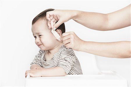 ear (all meanings) - Hands applying plaster to baby's face Photographie de stock - Premium Libres de Droits, Code: 614-08876077