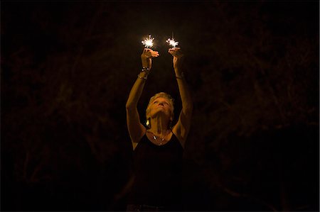 Mature woman with sparklers at night on independence day, Destin, Florida, USA Stock Photo - Premium Royalty-Free, Code: 614-08876317