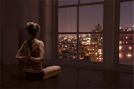 Woman practising yoga by window Stock Photo - Premium Royalty-Free, Code: 614-08876423