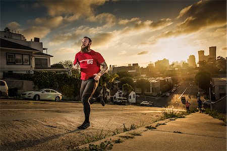 streets and buildings of california - Mid adult male runner and team mates running up a steep city hill Stock Photo - Premium Royalty-Free, Code: 614-08876602