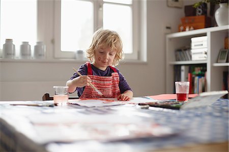 Young boy sitting at table, painting picture Stock Photo - Premium Royalty-Free, Code: 614-08877220