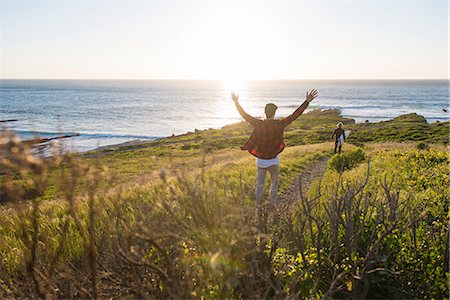 Young man with arms raised following surfer on coast path Foto de stock - Sin royalties Premium, Código: 614-08877397