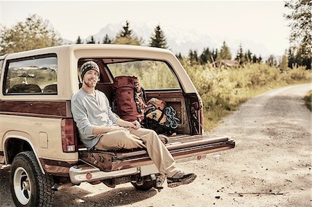 simsearch:614-08877825,k - Young man sitting on back of pickup truck, looking at camera, smiling Stock Photo - Premium Royalty-Free, Code: 614-08877818