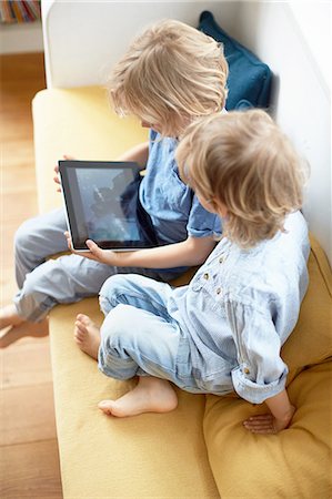 simsearch:649-09208789,k - Two young boys, sitting on sofa, looking at digital tablet Stock Photo - Premium Royalty-Free, Code: 614-08878196