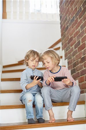 simsearch:649-09139274,k - Two young boys, sitting on stairs, looking at smartphones Stock Photo - Premium Royalty-Free, Code: 614-08878197