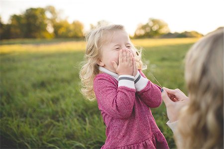dressing - Mid adult woman tickling daughters face with stem of grass in field Stock Photo - Premium Royalty-Free, Code: 614-08878511