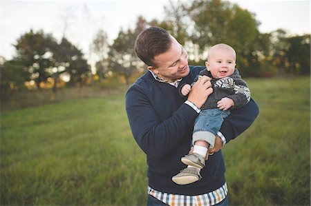 simsearch:614-08535901,k - Mid adult man carrying baby son in field Stock Photo - Premium Royalty-Free, Code: 614-08878512