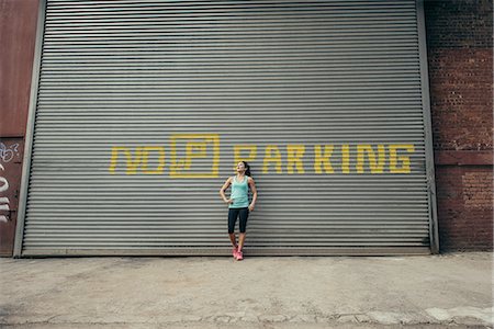 simsearch:649-07905288,k - Young female runner leaning against shutter Stock Photo - Premium Royalty-Free, Code: 614-08878685