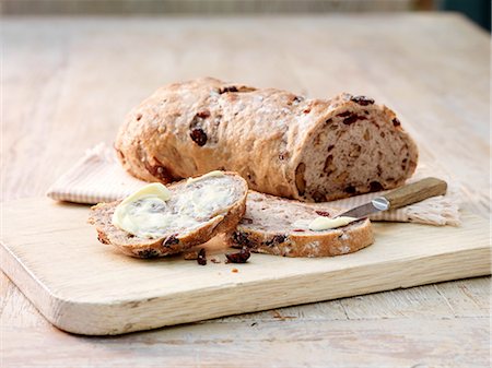 Sliced fruit and nut sourdough bread smeared with butter and butter knife Photographie de stock - Premium Libres de Droits, Code: 614-08878727