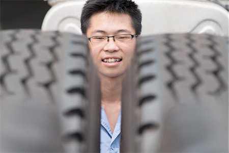 Head portrait of male factory worker between truck tyres in crane factory, China Stock Photo - Premium Royalty-Free, Code: 614-08878844