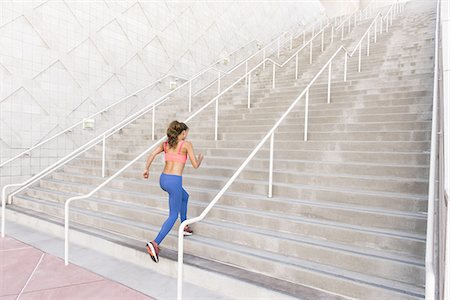 staircase of challenges - Rear view of young woman wearing sports clothing running up stairs Stock Photo - Premium Royalty-Free, Code: 614-08879013