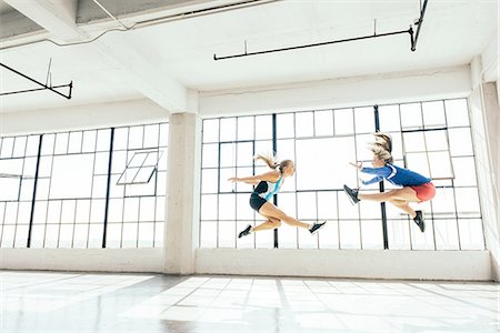 simsearch:628-01586462,k - Low angle side view of young women in gym doing mid air lunge Stock Photo - Premium Royalty-Free, Code: 614-08879107