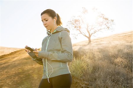 simsearch:649-09111305,k - Female runner on sunlit hill choosing smartphone music Photographie de stock - Premium Libres de Droits, Code: 614-08879148