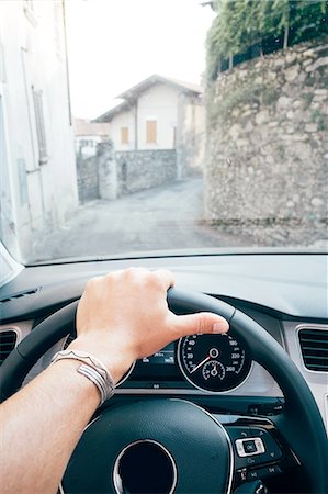 Hand on steering wheel and view through windscreen of narrow curving street, Luino, Lombardy, Italy Stock Photo - Premium Royalty-Free, Code: 614-08879263