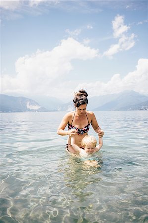 Front view of mother waist deep in lake holding sons hands, Luino, Lombardy, Italy Stock Photo - Premium Royalty-Free, Code: 614-08879294
