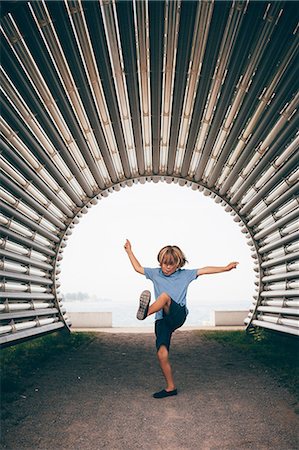 people dancing outdoors - Boy in corrugated tunnel, arm open leg raised Stock Photo - Premium Royalty-Free, Code: 614-08879330