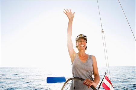 people boating - Smiling woman steering boat Stock Photo - Premium Royalty-Free, Code: 614-08870972