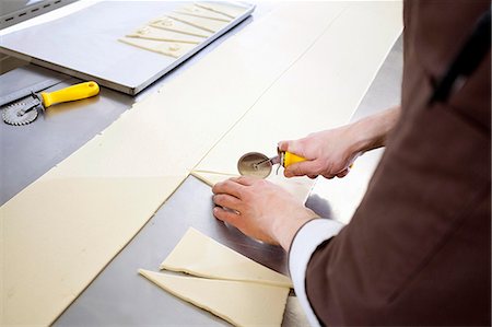 Baker cutting dough in kitchen Stock Photo - Premium Royalty-Free, Code: 614-08871081