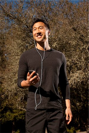 Man listening to earphones outdoors Stock Photo - Premium Royalty-Free, Code: 614-08871214