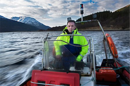 fishing boats scotland - Worker driving boat in rural lake Stock Photo - Premium Royalty-Free, Code: 614-08871308