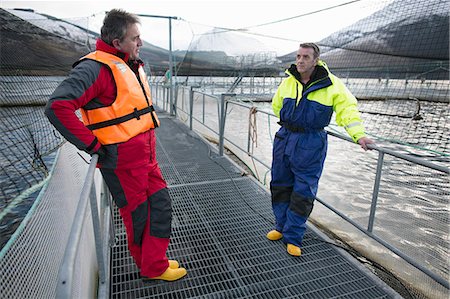 Workers at salmon farm in rural lake Stock Photo - Premium Royalty-Free, Code: 614-08871311