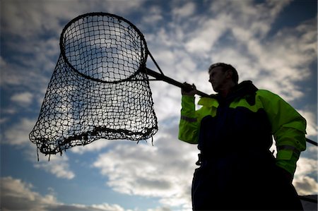 fishing silhouette - Worker with fishing net at salmon farm Stock Photo - Premium Royalty-Free, Code: 614-08871312