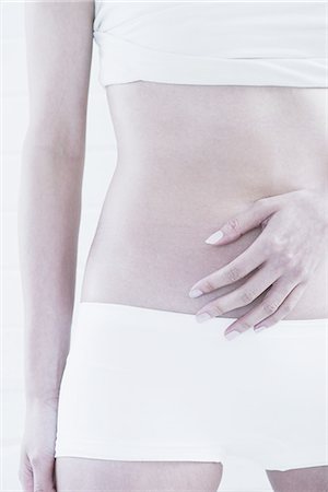 Woman's hand covering her belly Stock Photo - Premium Royalty-Free, Code: 614-08871377