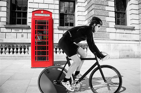 simsearch:614-08871945,k - Cyclist cycling past red telephone box Foto de stock - Sin royalties Premium, Código: 614-08871957