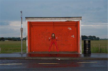 Teenage girl wearing red clothes at red bus stop Stock Photo - Premium Royalty-Free, Code: 614-08872389