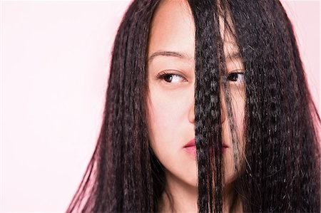 Woman with crimped hair covering face Stock Photo - Premium Royalty-Free, Code: 614-08872603