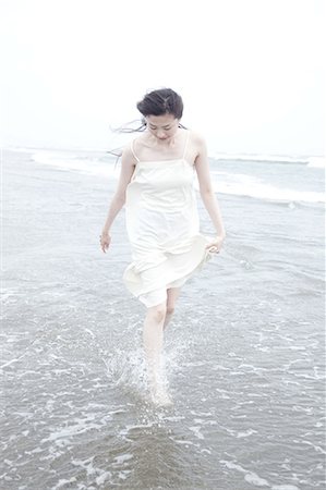 simsearch:614-07145859,k - Young woman with windswept hair paddling at water's edge Photographie de stock - Premium Libres de Droits, Code: 614-08872750
