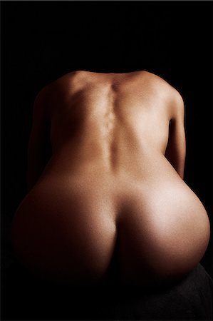 Naked woman sitting in dark, rear view Stock Photo - Premium Royalty-Free, Code: 614-08872885