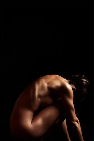 simsearch:614-08872881,k - Naked woman sitting in dark, side view Fotografie stock - Premium Royalty-Free, Codice: 614-08872886