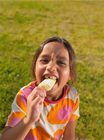 Girl biting into ice lolly, portrait Stock Photo - Premium Royalty-Free, Code: 614-08873146