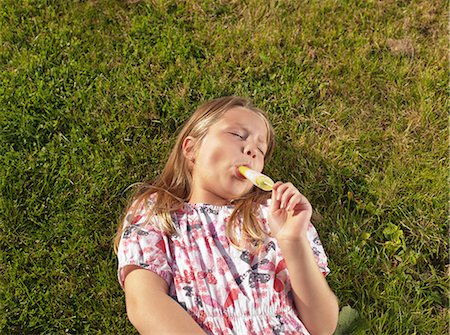 popsicle - Girl enjoying ice lolly on lawn Stock Photo - Premium Royalty-Free, Code: 614-08873147