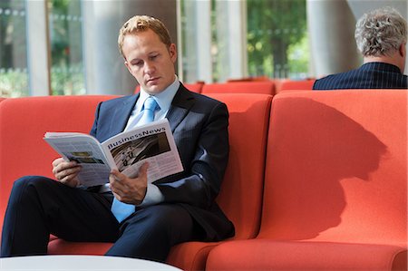 Businessman reading magazine in office lobby Stock Photo - Premium Royalty-Free, Code: 614-08873201