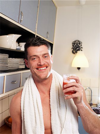 Mid adult man enjoying fruit drink in kitchen, portrait Stock Photo - Premium Royalty-Free, Code: 614-08873307