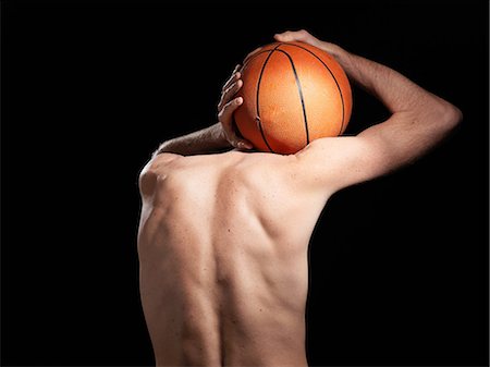 Rear view of semi-dressed basketball player against black background Stock Photo - Premium Royalty-Free, Code: 614-08873574