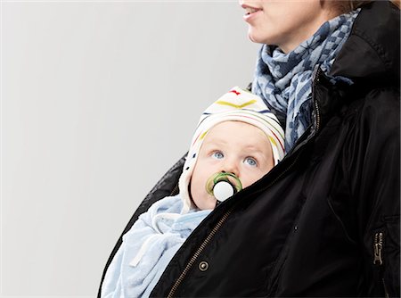 simsearch:6119-07845671,k - Baby tucked into mother's jacket, studio shot Fotografie stock - Premium Royalty-Free, Codice: 614-08873570