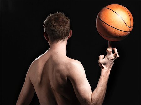 Rear view of semi-dressed basketball player against black background Stock Photo - Premium Royalty-Free, Code: 614-08873573