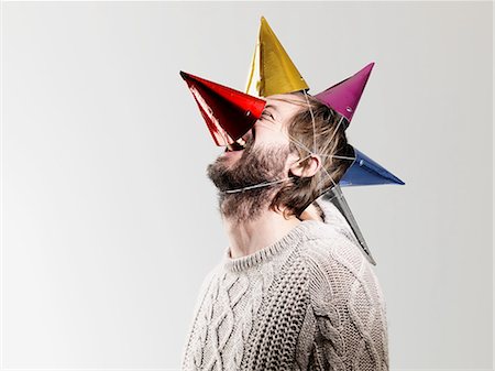 Mid adult man in party hats against white background Stock Photo - Premium Royalty-Free, Code: 614-08873580