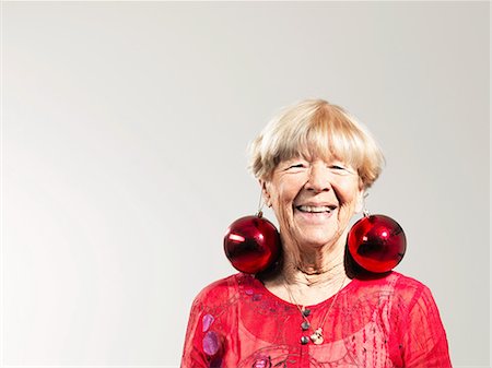 funny hairdo - Senior woman wearing red baubles as earrings against white background Stock Photo - Premium Royalty-Free, Code: 614-08873595