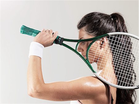 Woman holding tennis racket against white background Stock Photo - Premium Royalty-Free, Code: 614-08873597