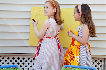 sell lemonade - Girls making sign for selling homemade lemonade Stock Photo - Premium Royalty-Free, Code: 614-08873963